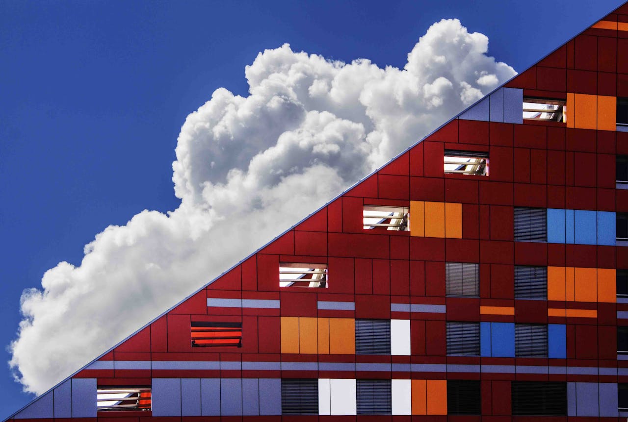 Mastering the First Impression: Your intriguing post title goes here Colorful modern building facade against a backdrop of dramatic clouds and bright blue sky.